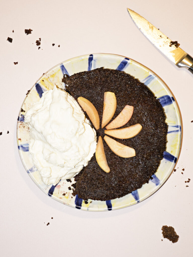 Apfel-Schwarzbrot-Charlotte angerichtet mit einem großen Klecks Marillen-Schlagsahne