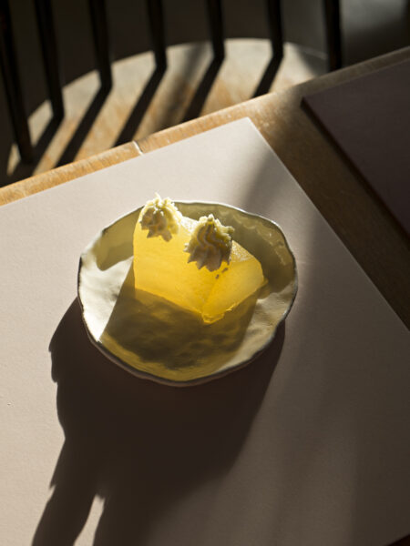 Ein Stück Apfel-Wackelpudding mit zwei Schlagsahnehäubchen im Gegenlicht