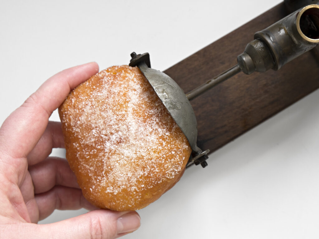 Konfitüre wird in Krapfen mit Füllgerät gefüllt